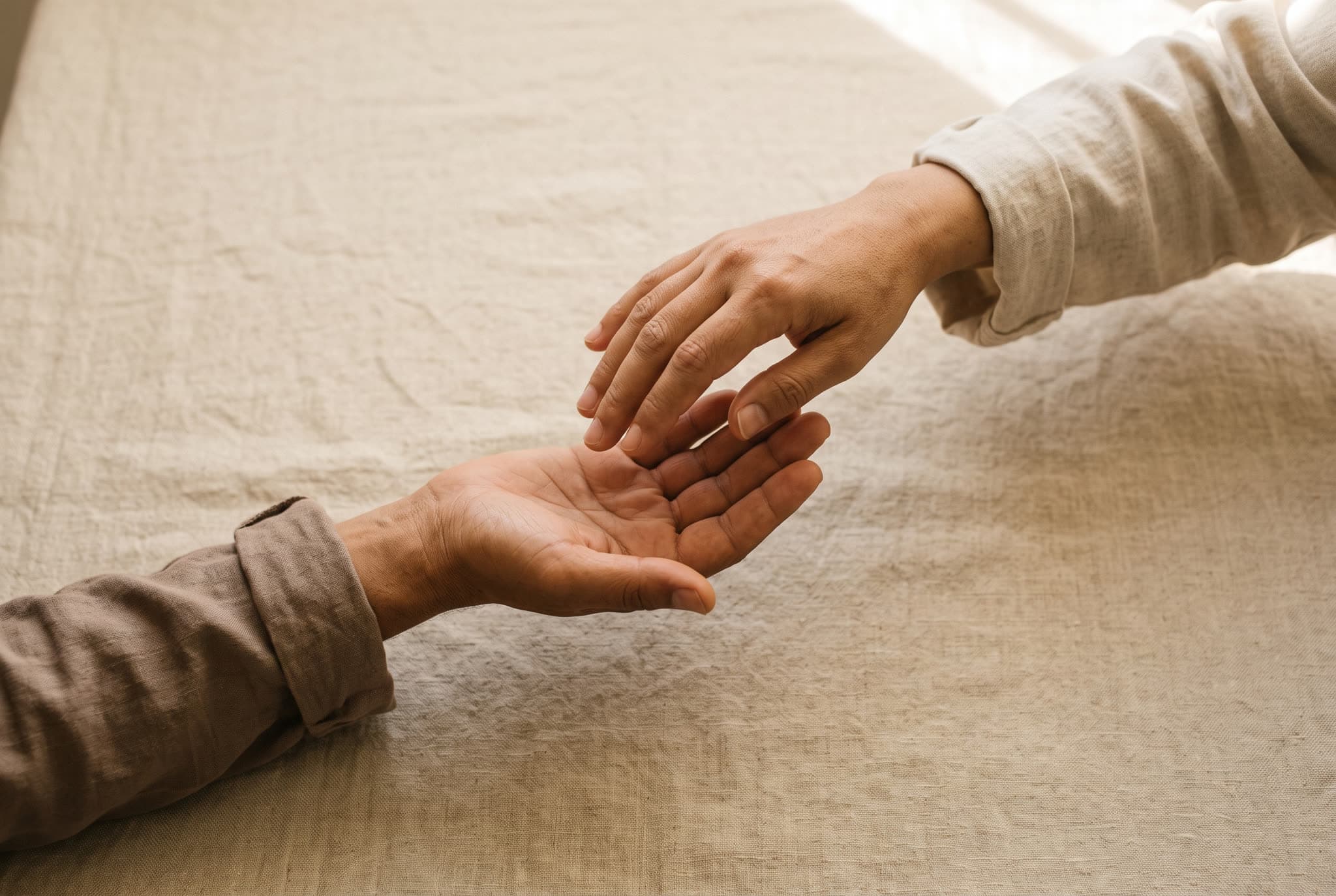 Two empty hands meeting, seen from above: one open palm offering, the other receiving.